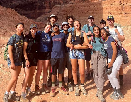 A group of men and women students posing in front of red rock formations.